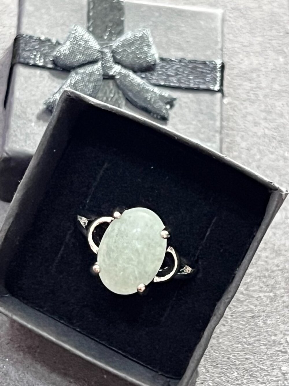Elegant silver-tone ring featuring an oval pale green cabochon stone with openwo